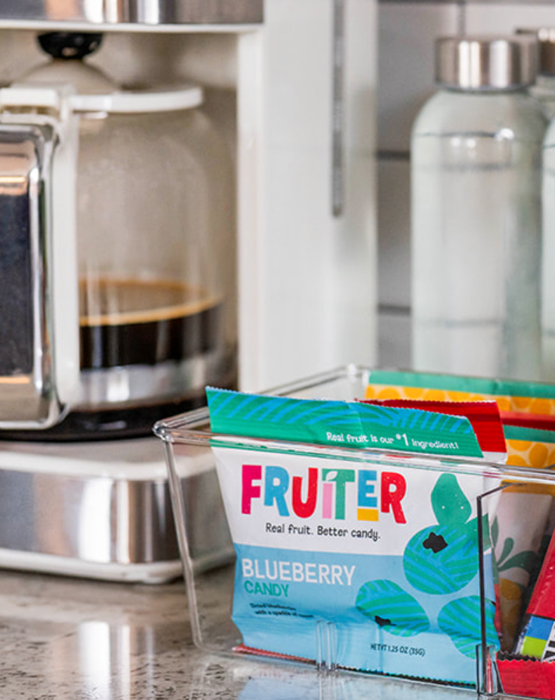 Fruiter all-natural dried blueberry, cherry, and cranberry candy individual snack packs in a container in an office break room for employees to have a healthy sweet treat. Fruiter candy comes in sweet, sweet and sour, and super sour varieties.